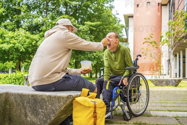 Disabled university student with cerebral palsy eating with a friend in the campus