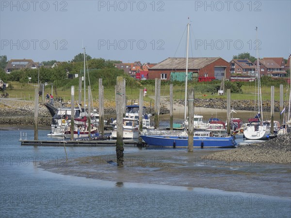 Harbour with sailing boats and houses on the shore under a clear blue summer sky, Baltrum Germany