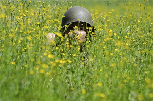 Scary Woman with Military Helmet Hidden in the Field with Yellow Flowers in a Sunny Day in