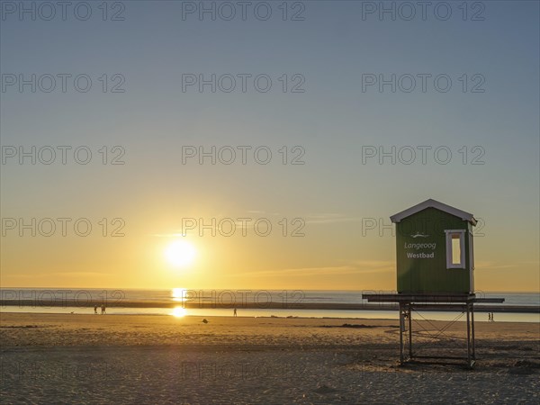 Sunset on the beach with a green wooden hut, peaceful sea and golden sky, evening mood on the beach