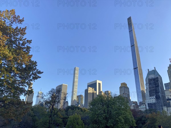 Central park in autumn with towering modern skyscrapers in the background, the skyline of new york