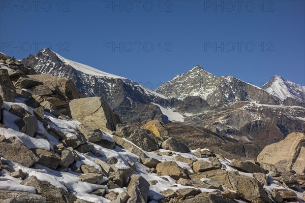 Striking mountain peaks and rock formations covered with snow under a bright blue sky, bare