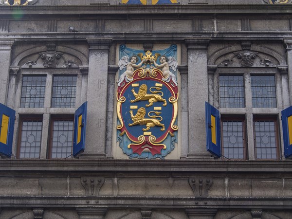 Coat of arms decorated building facade with windows and ornate architectural details, historic