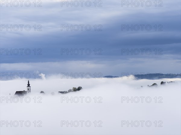 Church tower rises out of the morning mist, Frauenberg pilgrimage church, near Leibnitz, Styria,