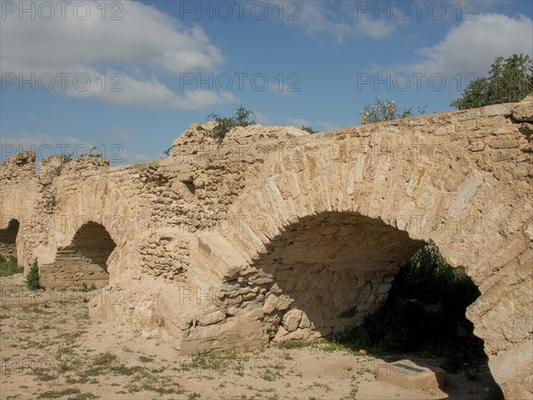 Massive, ancient stone arches of a city wall under a clear blue sky bear witness to past history,