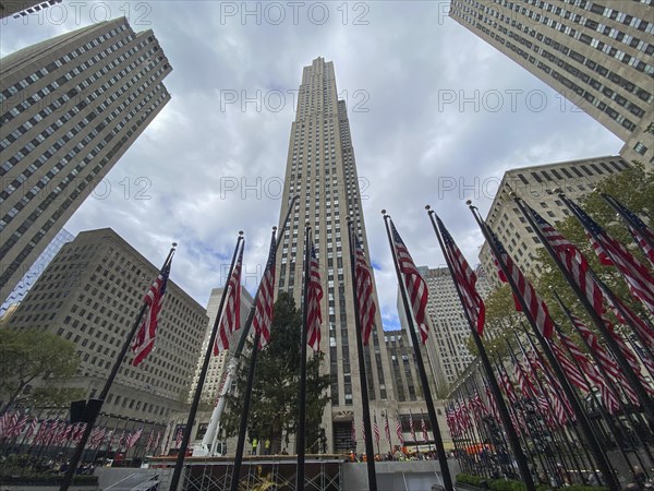 Tall skyscraper with several american flags in the foreground, surrounding tall buildings and