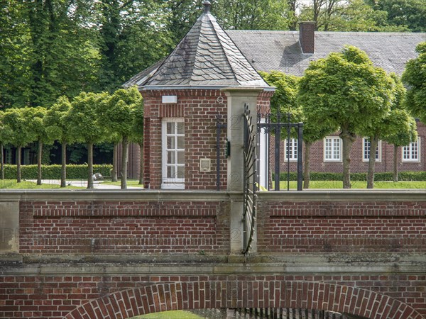 A small brick building with a Tor tor, surrounded by trees and a well-kept courtyard on a summer's