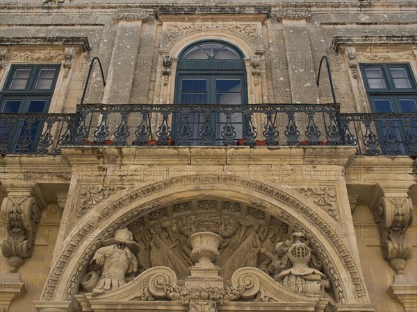 Close-up of a historic building with richly decorated balcony and stucco ornaments, the town of