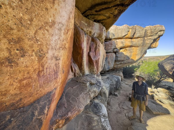 Young man looking at prehistoric depiction of woman on a rock, San rock paintings, Sevilla Art Rock