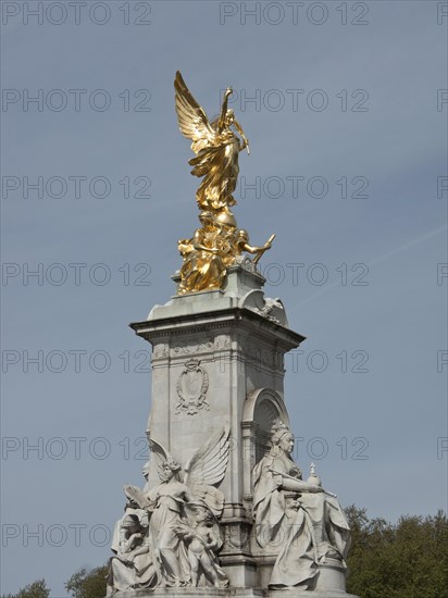 Golden angel statue rises on a marble pedestal, blue sky in the background, London, England, Great