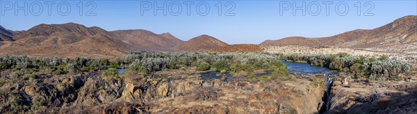 Panorama, Kunene River with green vegetation in dry red mountain landscape, waterfall and African