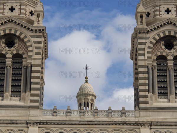Detailed close-up of the spires and a cross of a historic cathedral, blue sky in the background,