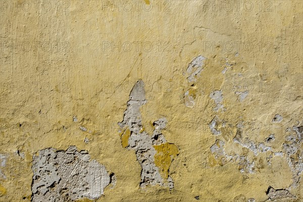 A weathered yellow wall with peeling paint and visible damage, Rhodes, Greece, Europe