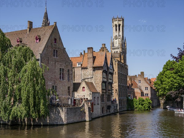 Historic buildings and a tall bell tower along a river on a sunny day, historic city by the river