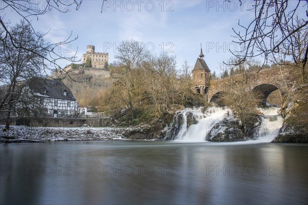 Beautiful landscape in winter with ice and snow. Waterfall of the river Elz near the castle
