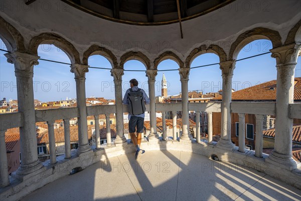 Young man looking over Venice with campanile, tower of Palazzo Contarini del Bovolo, palace with