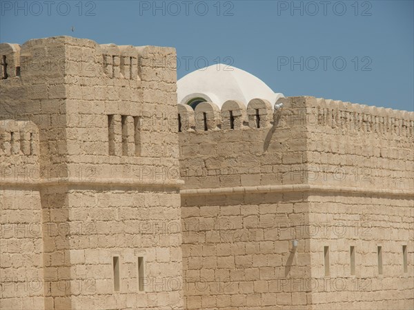 Stone walls of a historic fortress or castle with dome and clear sky, Tunis in Africa with ruins