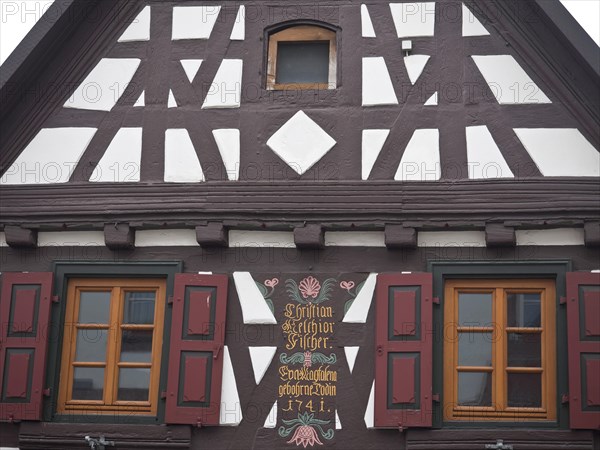A half-timbered house with a brown and white wooden structure and decorative shutters, kandel,