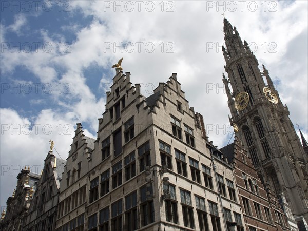 Historic buildings with ornate gables and a bell tower in the background under a blue sky with