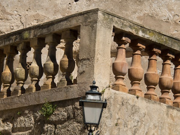 A stone balustrade on an old wall with a lamp, palma de mallorca on the mediterranean sea with its