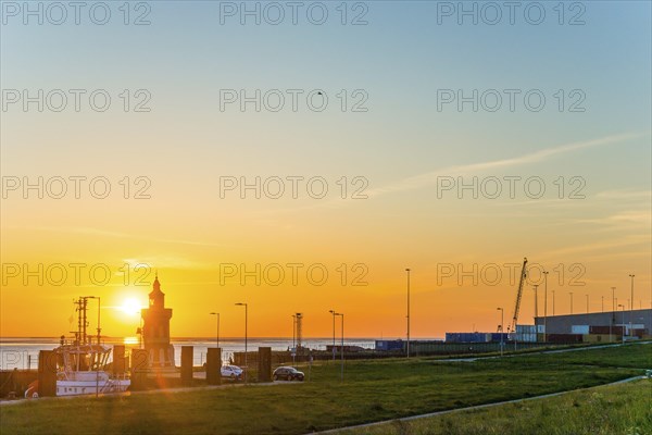 Pingelturm, historic lighthouse at the harbour at sunset, with calm sea, boats and green meadow in