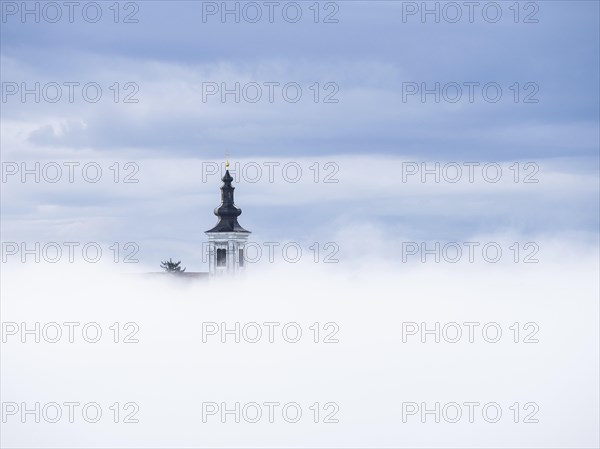 Church tower rises out of the morning mist, Frauenberg pilgrimage church, near Leibnitz, Styria,