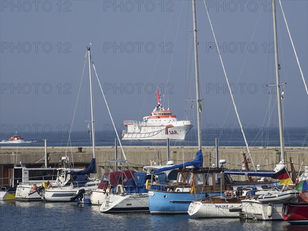 Harbour view with sailboats and a SAR rescue ship in the blue sea under a clear sky, Helgoland,