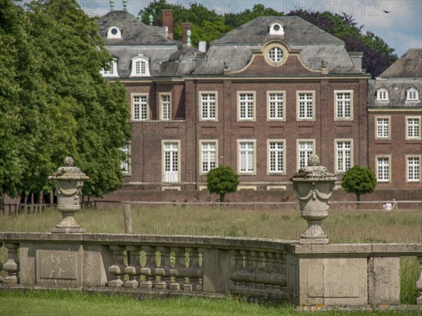 Stone vases in a green park, with a historic castle in the background, historic castle with a green
