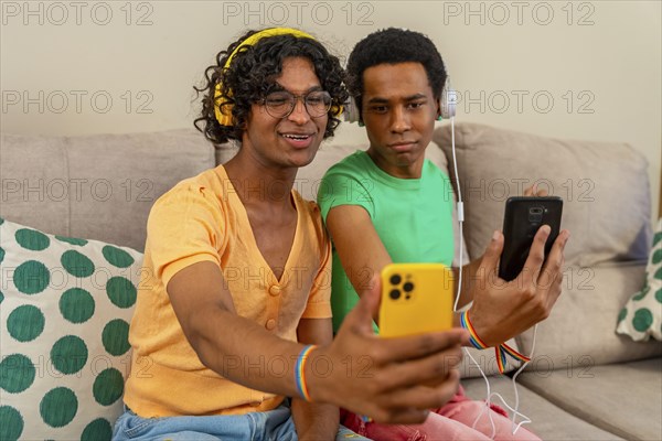 Gay couple listening to music and taking a selfie together at home