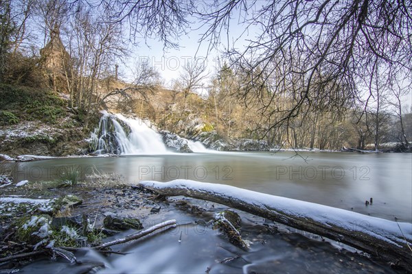 Beautiful landscape in winter with ice and snow. Waterfall of the river Elz near the castle