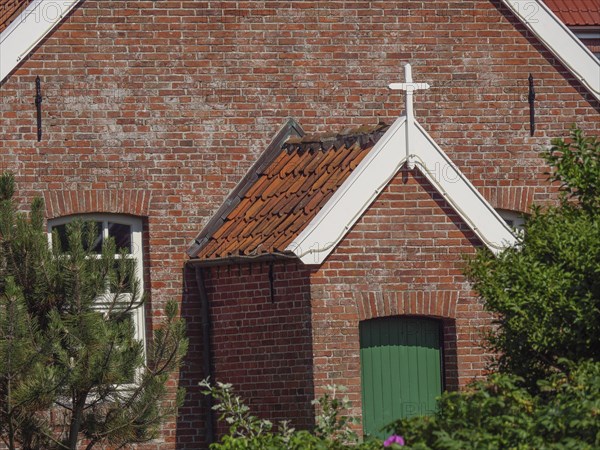 View of a brick church building with green painted door and white cross above, Baltrum Germany