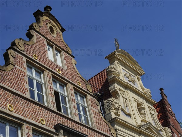 Historic brick building with decorative ornaments under a clear blue sky, medieval facades with