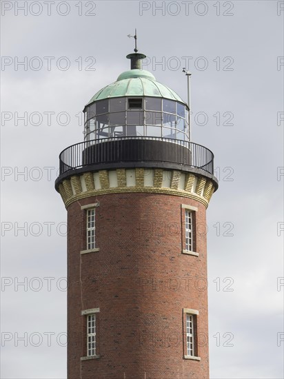 Brick lighthouse with green dome under a partly cloudy sky, Cuxhaven, Germany, Europe