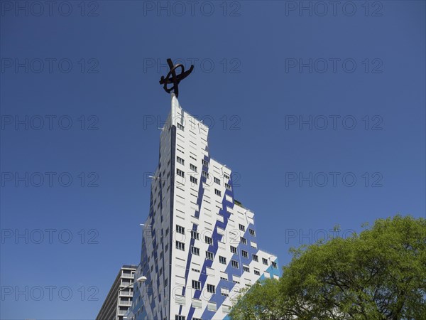 An ultra-modern building with an unusual design and strips of blue windows in bright sunshine,