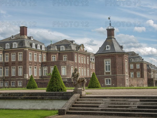Imposing castle building in a park-like setting with clouds in the sky, historic castle with a