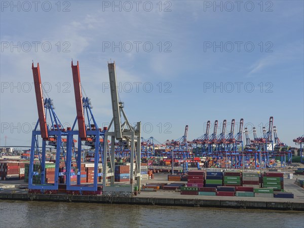 An industrial harbour terminal with lots of containers, cranes and storage areas on a sunny day, a