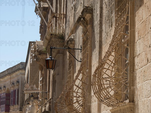 Historic street with stone facades and lanterns in a sunny town, the town of mdina on the island of