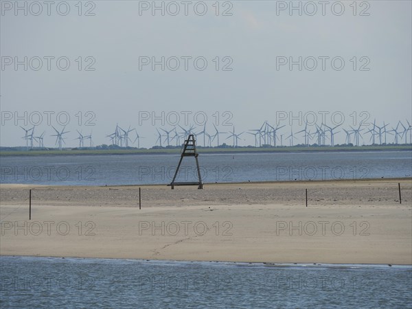 Sandy beach beach and the sea, in the background wind turbines under a slightly cloudy sky, Baltrum