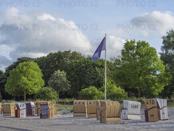 Beach chairs and green trees with a flag in the background, calm and relaxed atmosphere on the