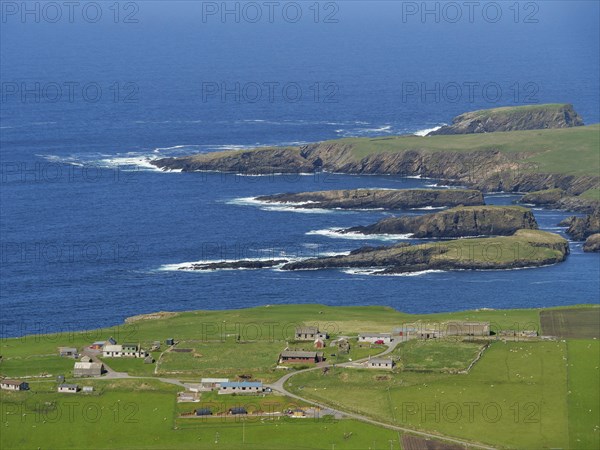 Coastal landscape with green fields, scattered houses and rocky cliffs by the deep blue sea, Green