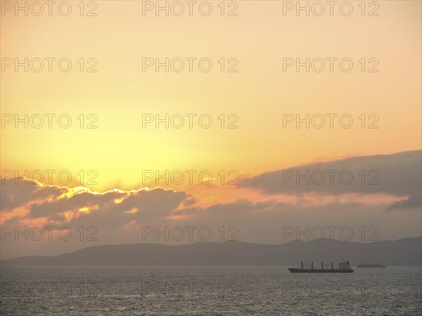 A large ship sails under an orange sunset on the calm sea, Tunis in Africa with ruins from Roman