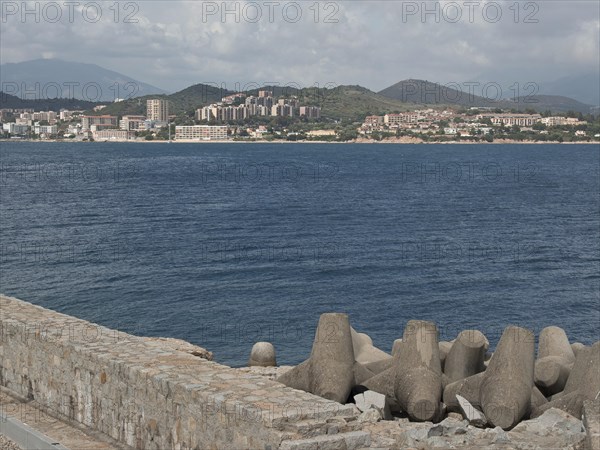View of a coastal town across the sea, concrete breakwater in the foreground, Corsica, ajaccio,