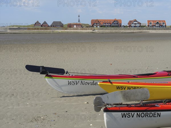 Kayaks on the beach with village and blue sky in the background, Baltrum Germany