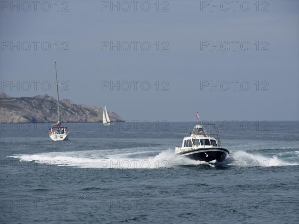 Boats on the sea, waves crashing against rocks under a blue sky, Marseille on the Mediterranean Sea