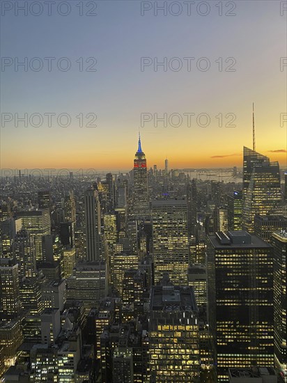 Cityscape at dusk with illuminated skyscrapers and the Empire State Building in the centre, the