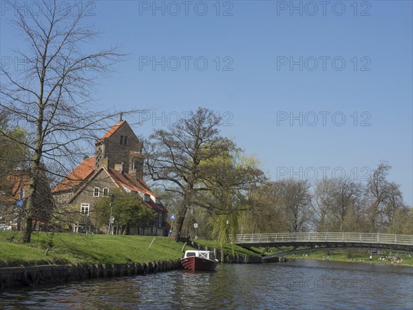 Landscape with a riverside church, a picturesque bridge and a boat on the water, Haarlem,