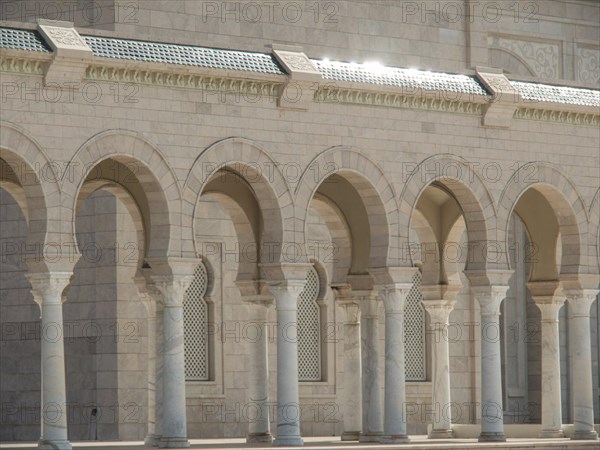 A sun-drenched building with marble columns and arcades that hints at historical significance,