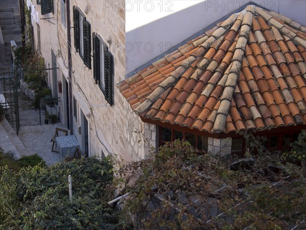 Stone buildings with tiled roofs and plants protruding into the narrow outdoor area, the old town