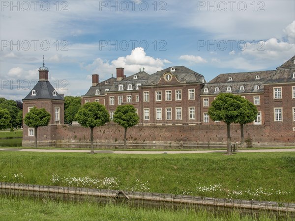 Historic brick castle with manicured lawn and trees under a cloudy sky, historic castle with a