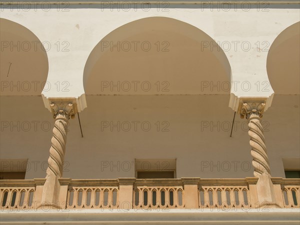 White and beige arcaded structures with columns and balconies, Tunis in Africa with ruins from